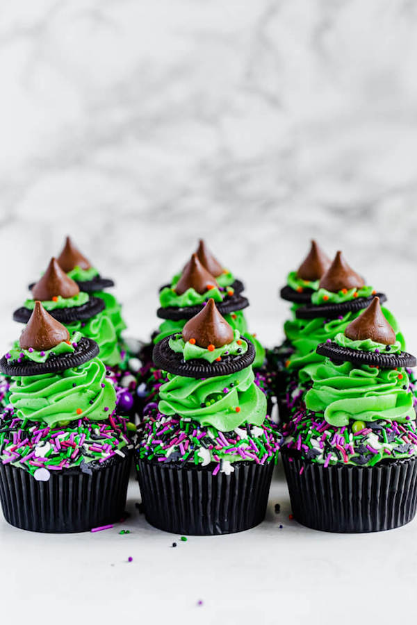 black chocolate cupcakes topped with green buttercream and witch hats