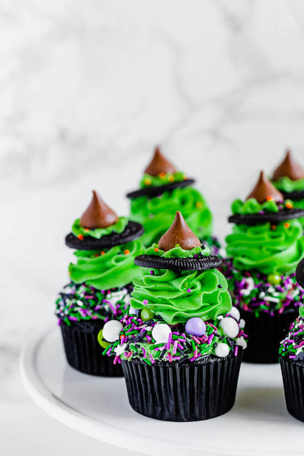 black chocolate cupcakes topped with green buttercream and witch hats