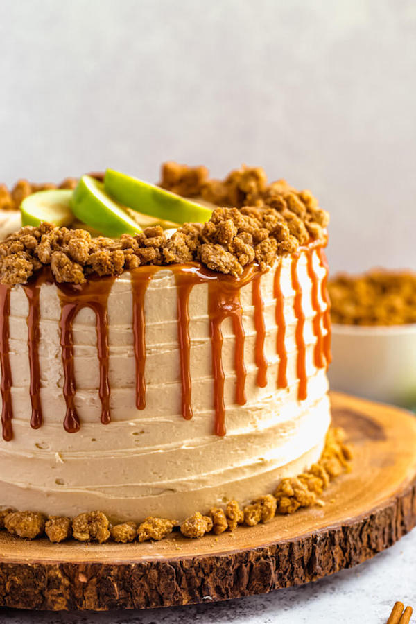 side view of caramel apple crumble cake on a wooden cake stand