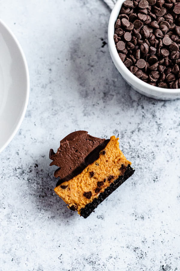 mini pumpkin cheesecake cut in half with a bowl of chocolate chips at the side