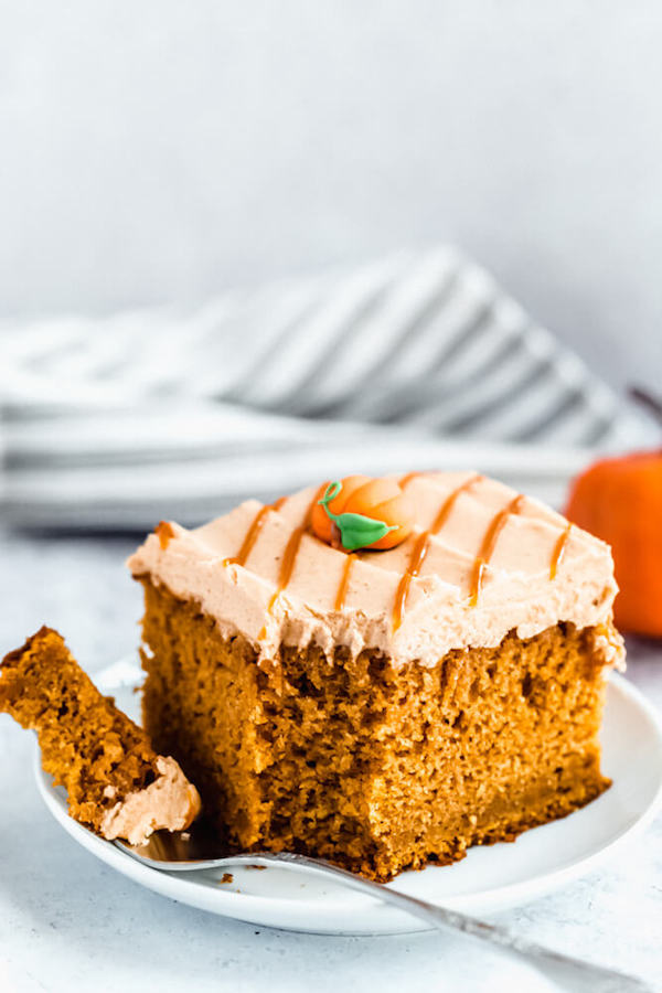 slice of pumpkin cake topped with caramel pumpkin spice cream cheese frosting