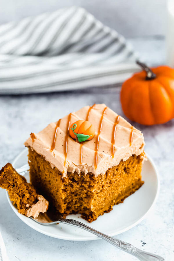 slice of pumpkin cake topped with caramel pumpkin spice cream cheese frosting