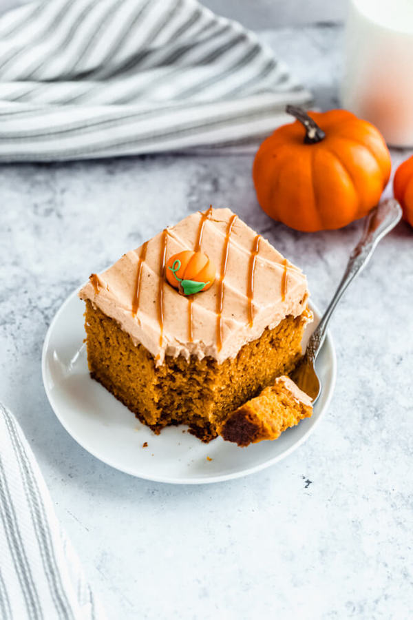 slice of pumpkin cake topped with caramel pumpkin spice cream cheese frosting