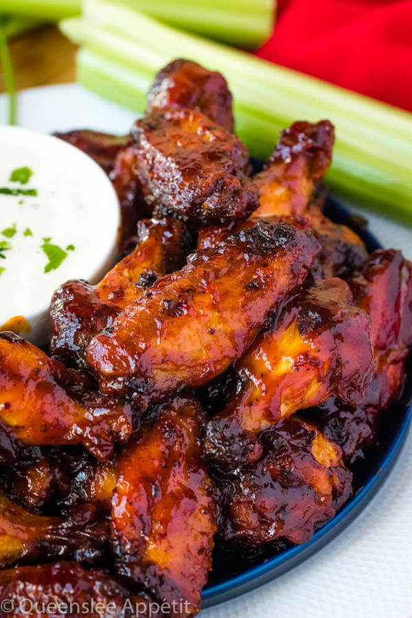 honey barbecue flavoured chicken wings on a blue plate with ranch dipping on the side