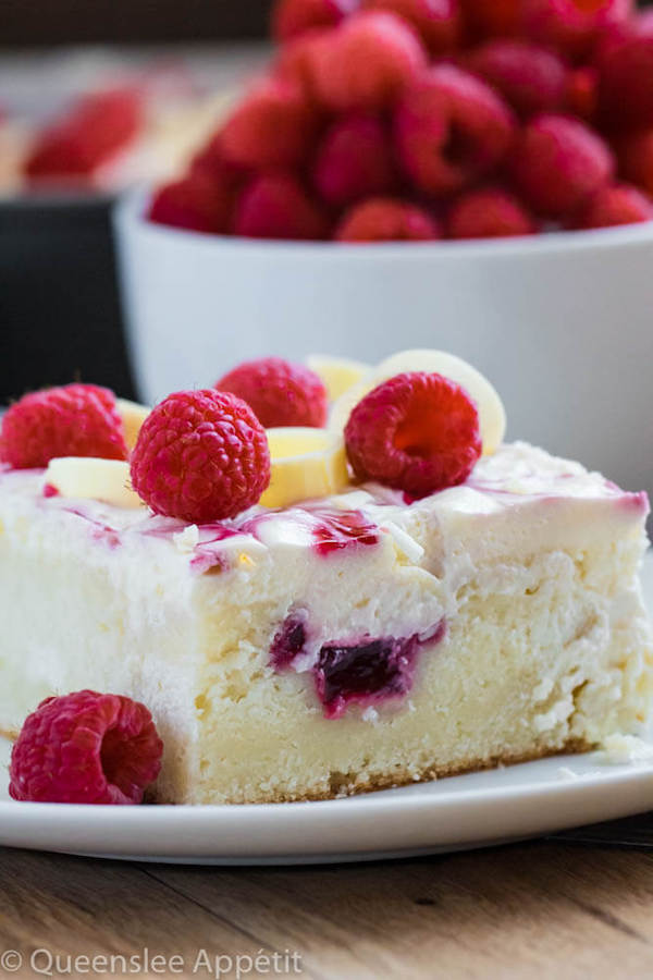 slice of white sheet cake with raspberries on top