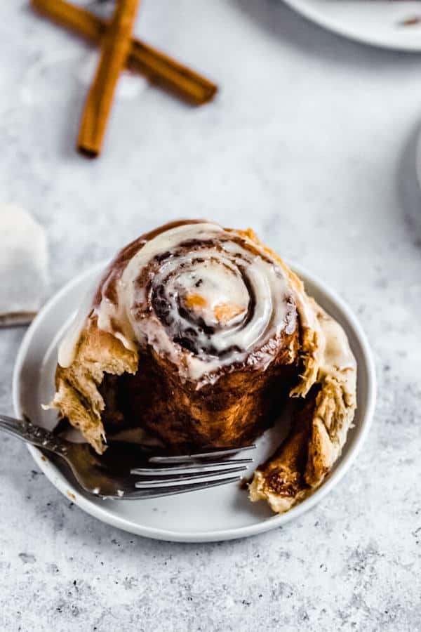 half eaten cinnamon roll on a small plate 