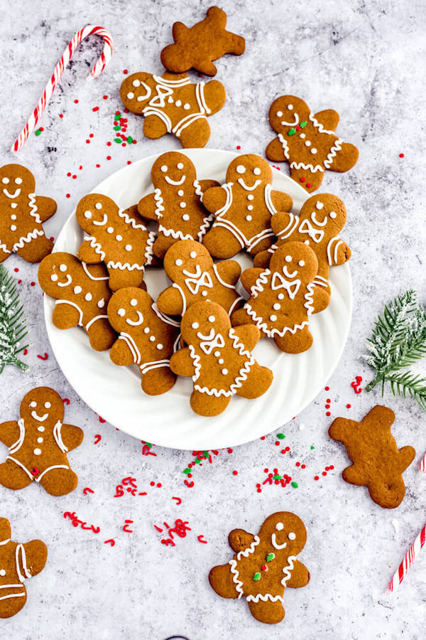 gingerbread man cookies on a white plate surrounded by more cookies