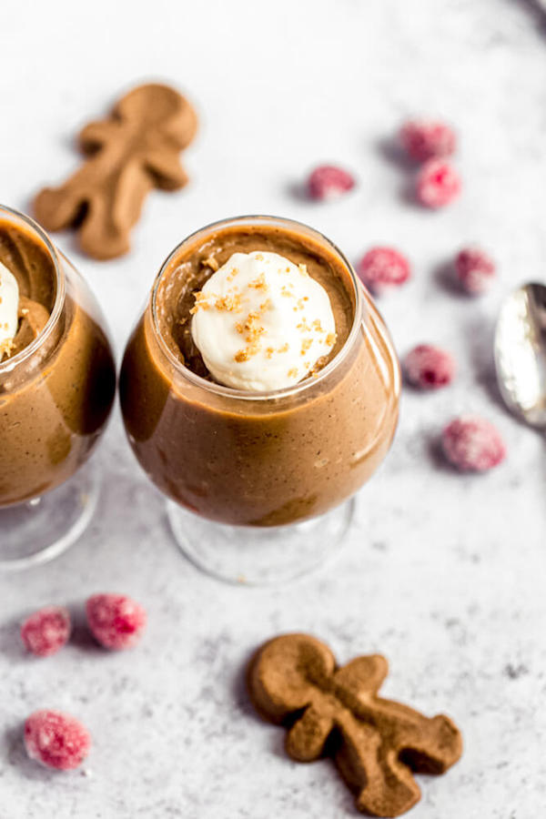 gingerbread pudding topped with eggnog whipped cream surrounded by sugared cranberries and gingerbread men