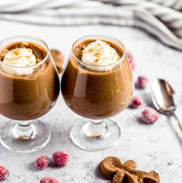 two glasses of gingerbread pudding surrounded by sugared cranberries and gingerbread men