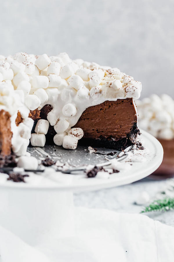 cut open chocolate flavoured cheesecake with marshmallow fluff and marshmallows sliding down middle