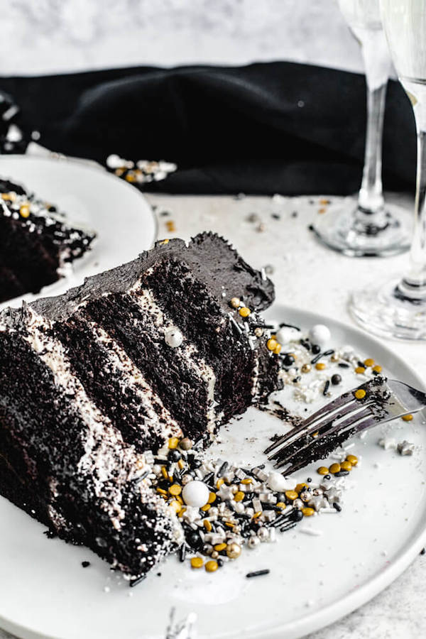 close up of half eaten black chocolate cake with sprinkles on plate