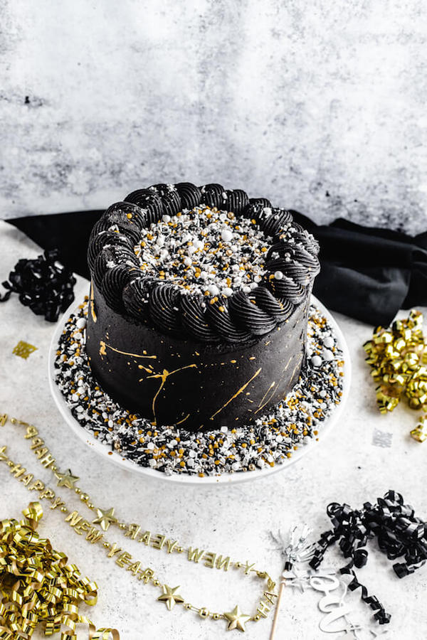 gold and black cake with sprinkles on top and around the bottom