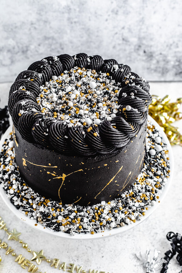 black and gold sprinkle cake on a cake stand