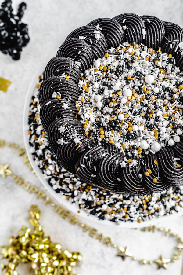 top view of black and gold cake with sprinkles in the centre