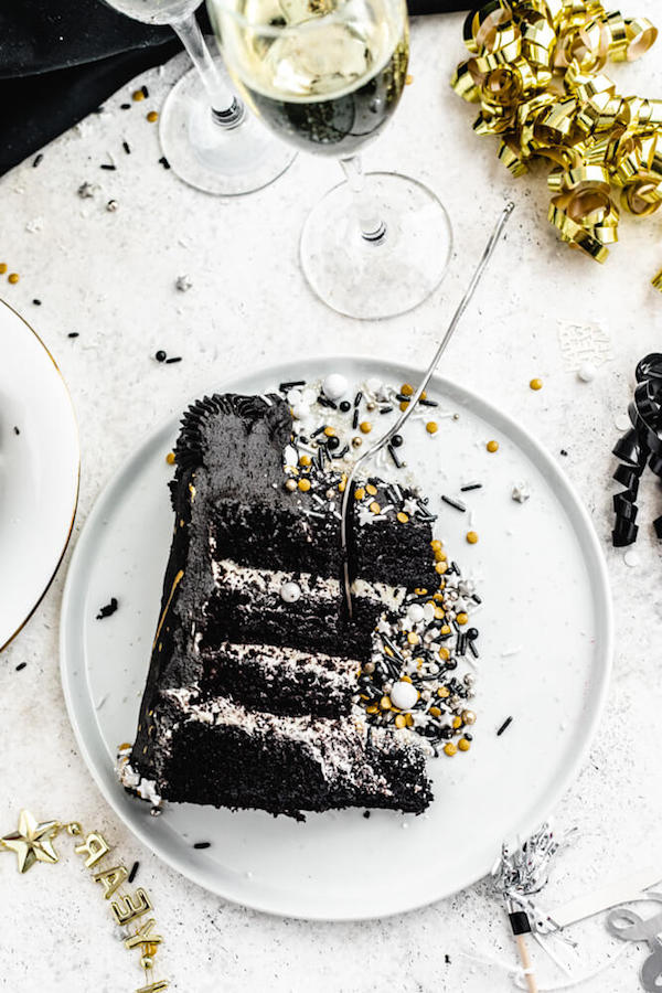 slice of black chocolate cake on a white plate with fork inside