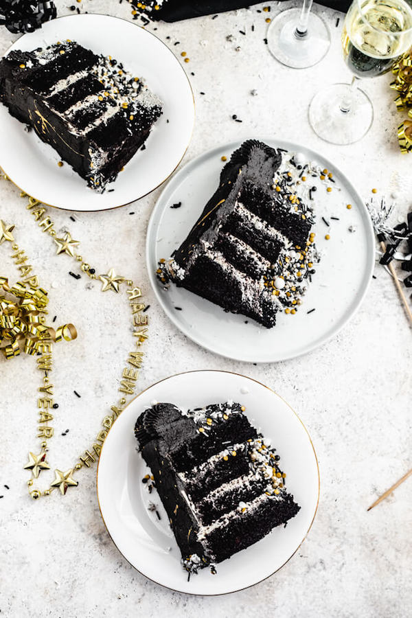 three slices of black cake on white plates