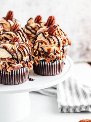 chocolate caramel pecan cupcakes on a white cake stand