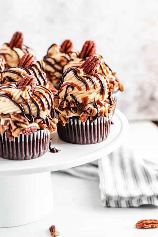 chocolate caramel pecan cupcakes on a white cake stand