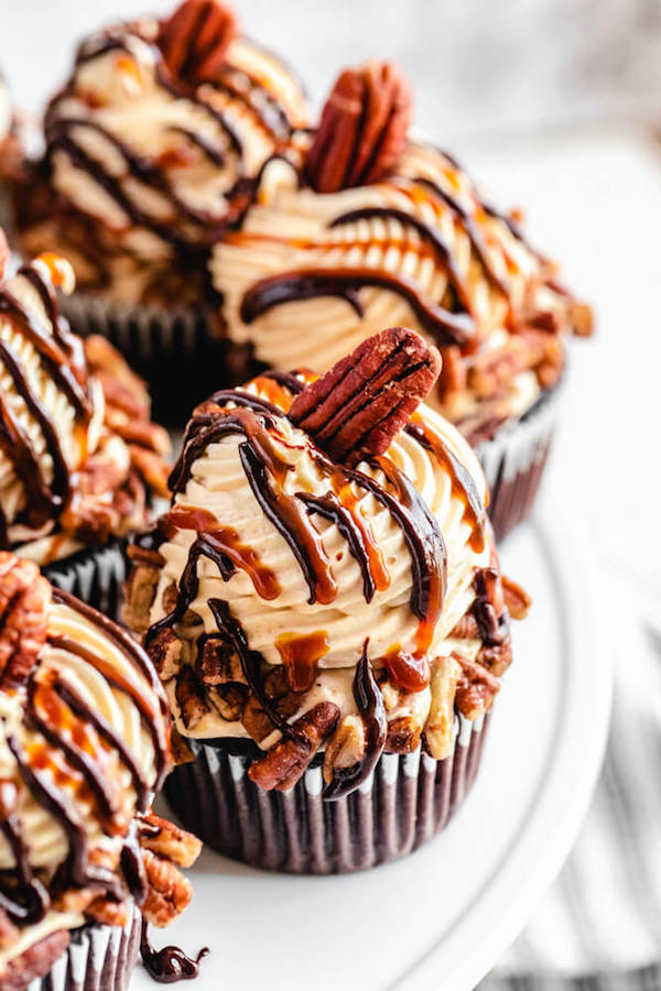 close up of turtle pecan cupcakes on a white cake stand