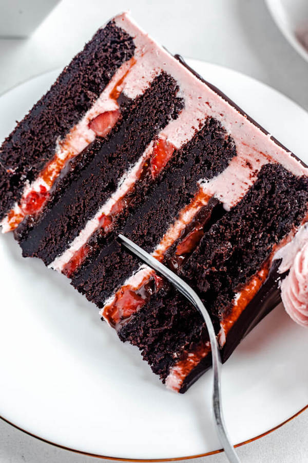 close up of a slice of cake on a white plate with fork inside