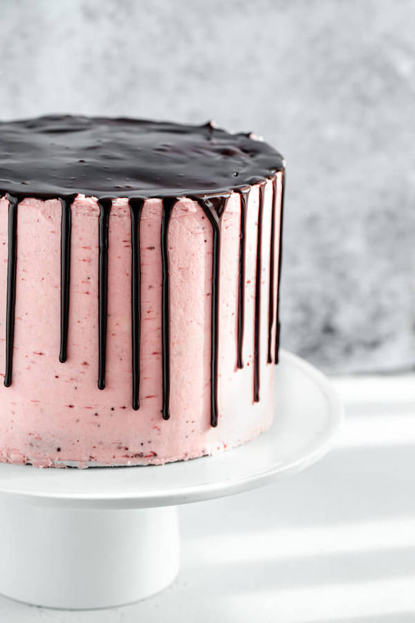 close up of strawberry frosted cake with ganache drip