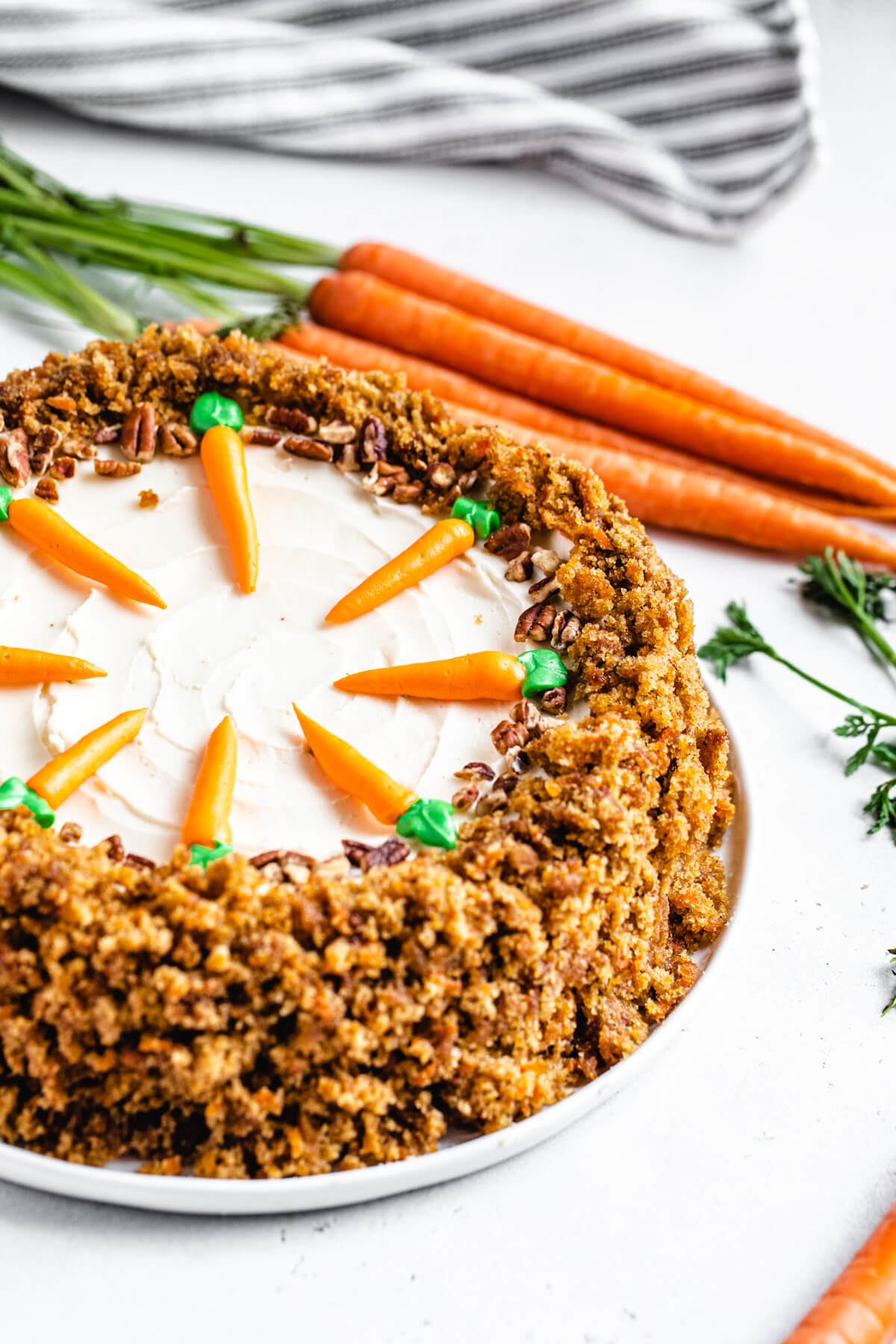 cheesecake on a white plate with carrots in the background