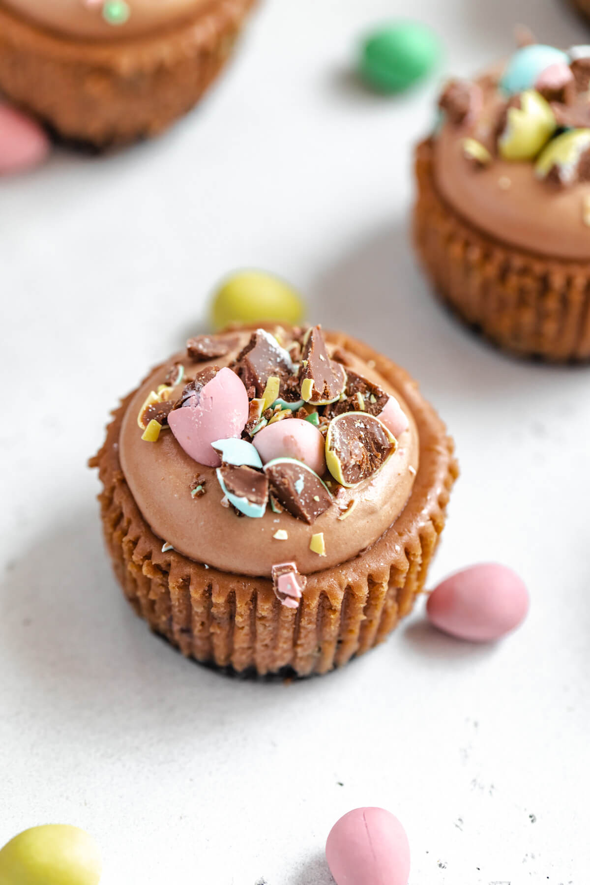 angled view of a bite-sized cheesecake surrounded by mini Easter eggs 