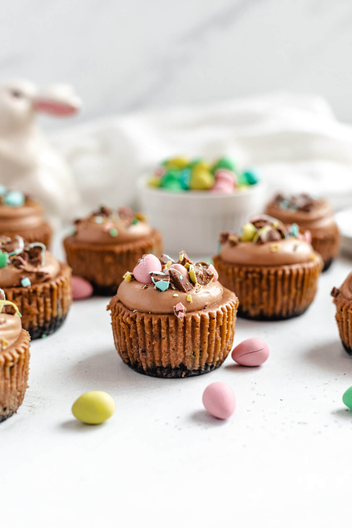 multiple mini cheesecakes topped with mousse and chopped chocolate eggs