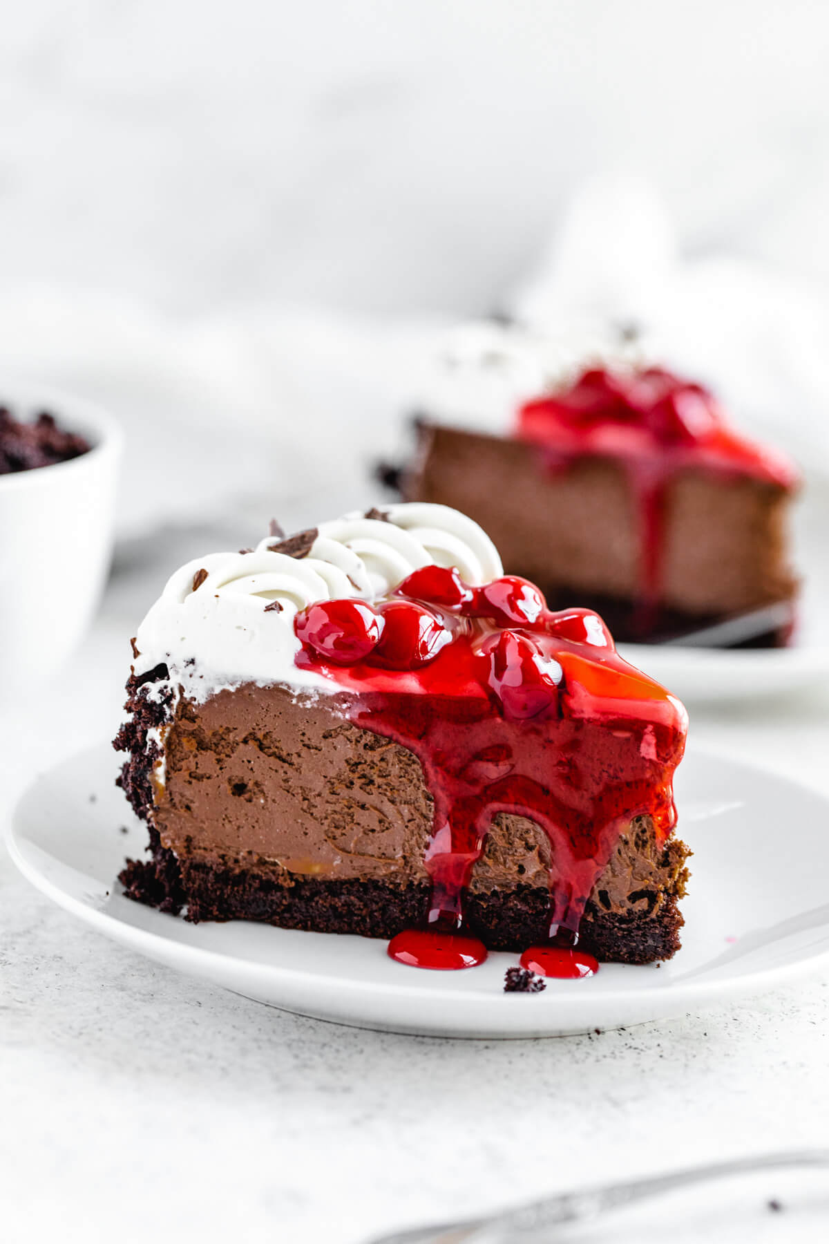 slice of cheesecake on a white plate with a second slice in the background