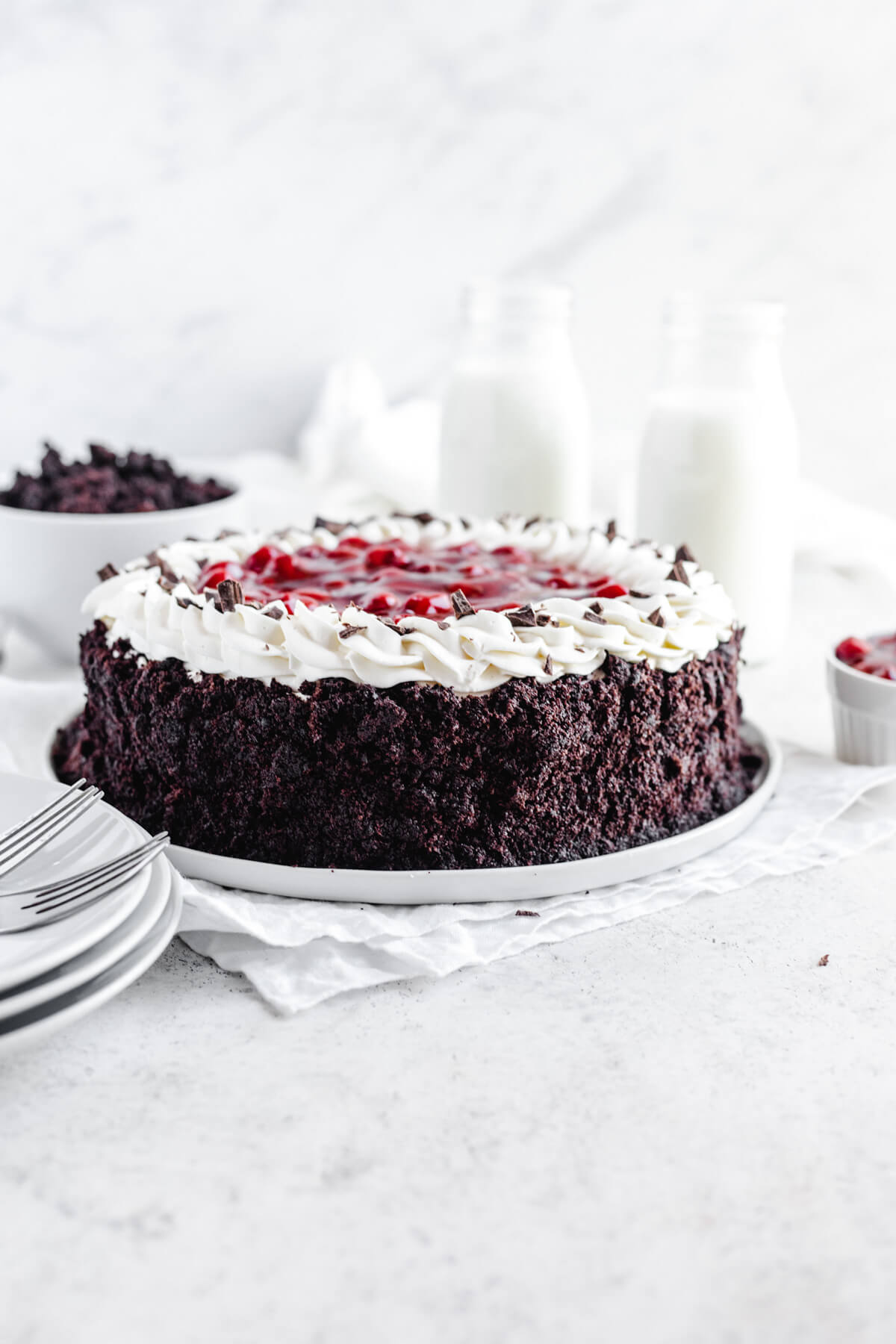 chocolate cake covered cheesecake on a white platter with white plates in the foreground