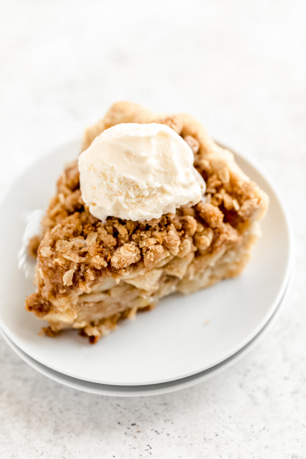 vanilla ice cream on top of a slice of pie in a white plate