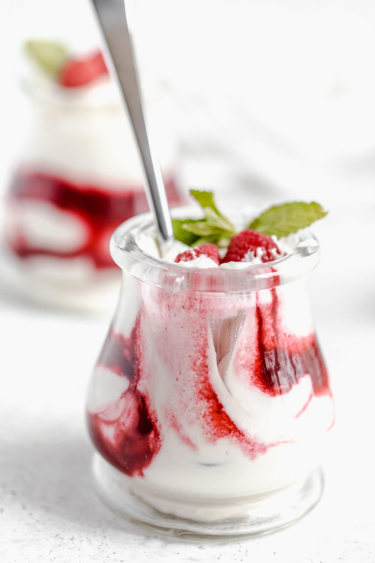 close up of half eaten jar of mousse and raspberry sauce