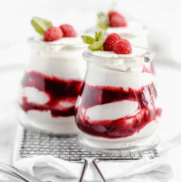 three jars of white chocolate mousse and raspberry sauce on a safety grater