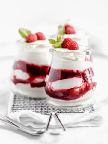 three jars of white chocolate mousse and raspberry sauce on a safety grater