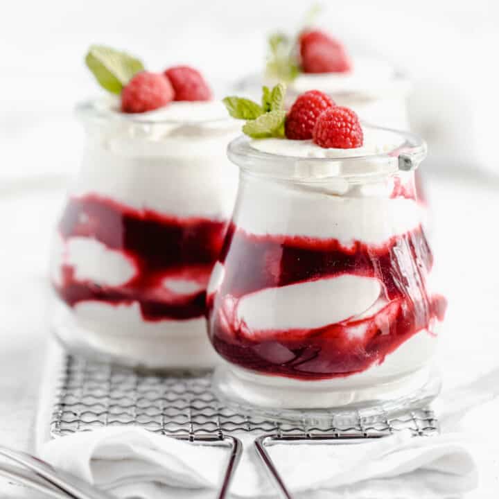 three jars of white chocolate mousse and raspberry sauce on a safety grater