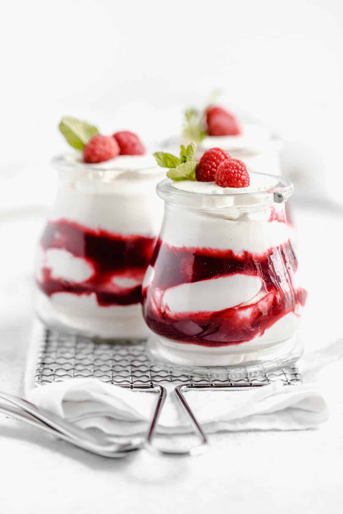 three jars of white chocolate mousse and raspberry sauce on a safety grater