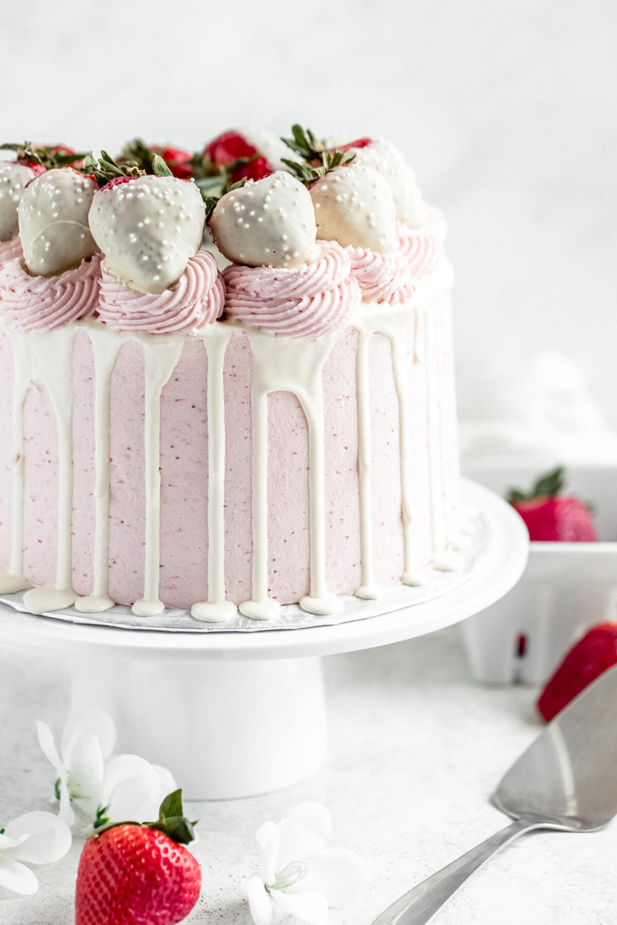 white chocolate and strawberry cake on a white cake stand