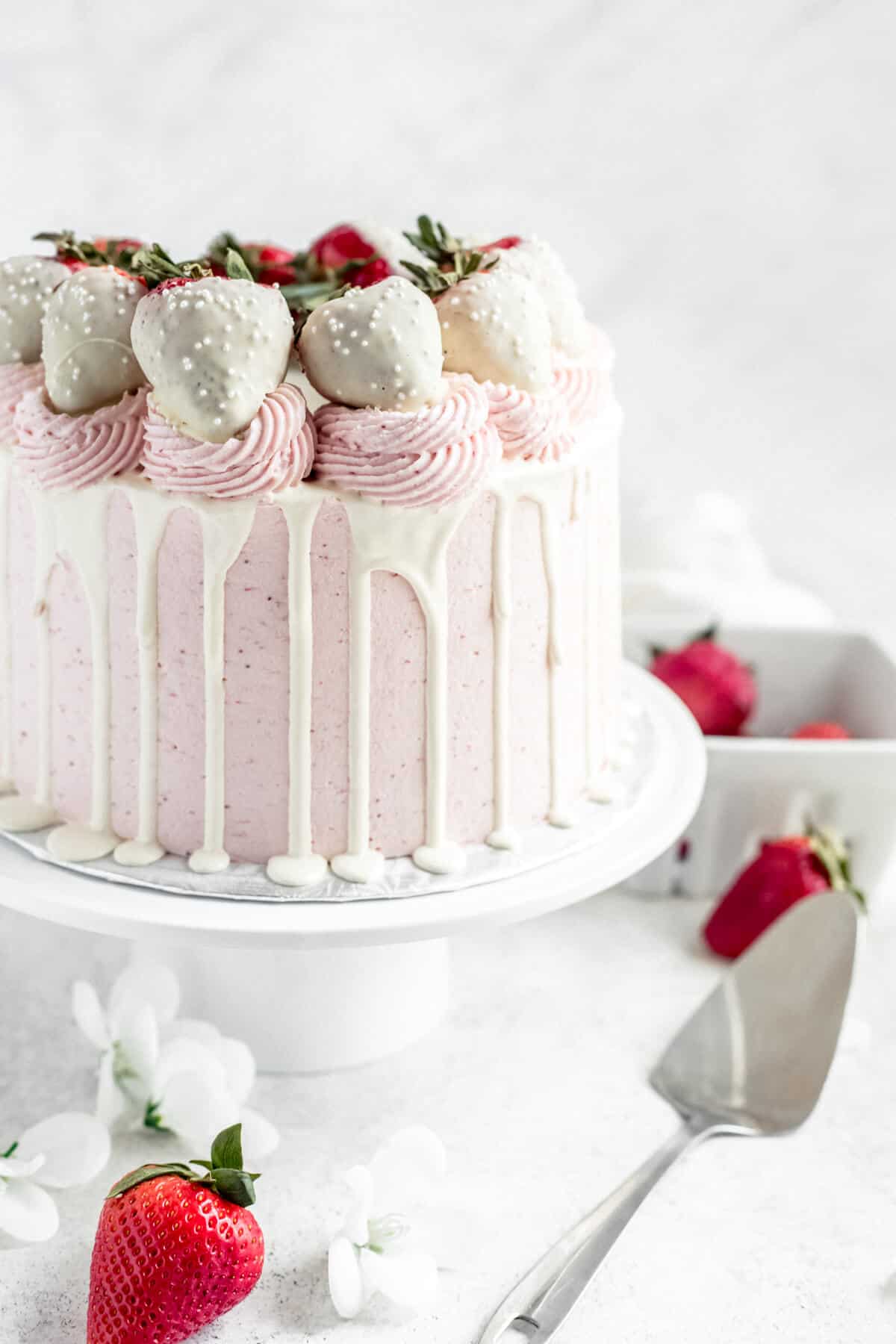 pink and white strawberry cake on a cake stand