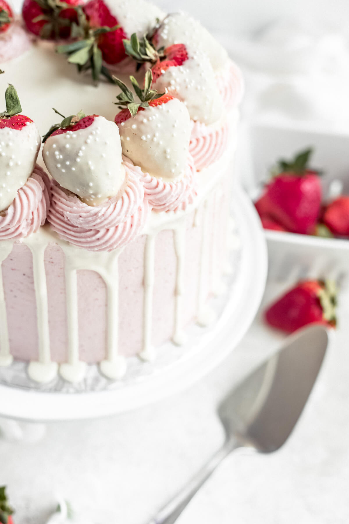 close up of white chocolate covered strawberries on top of a cake