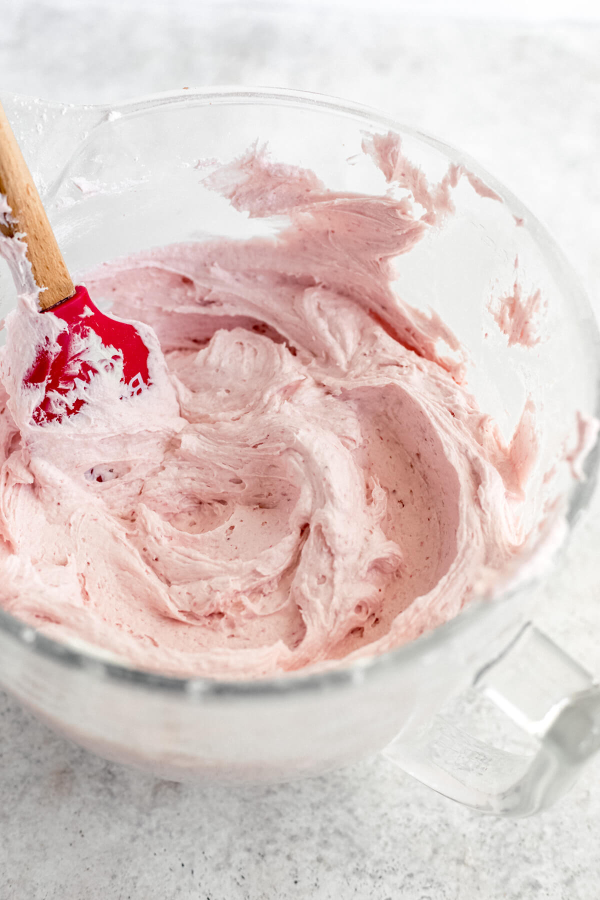 white chocolate strawberry frosting in a glass stand mixer bowl