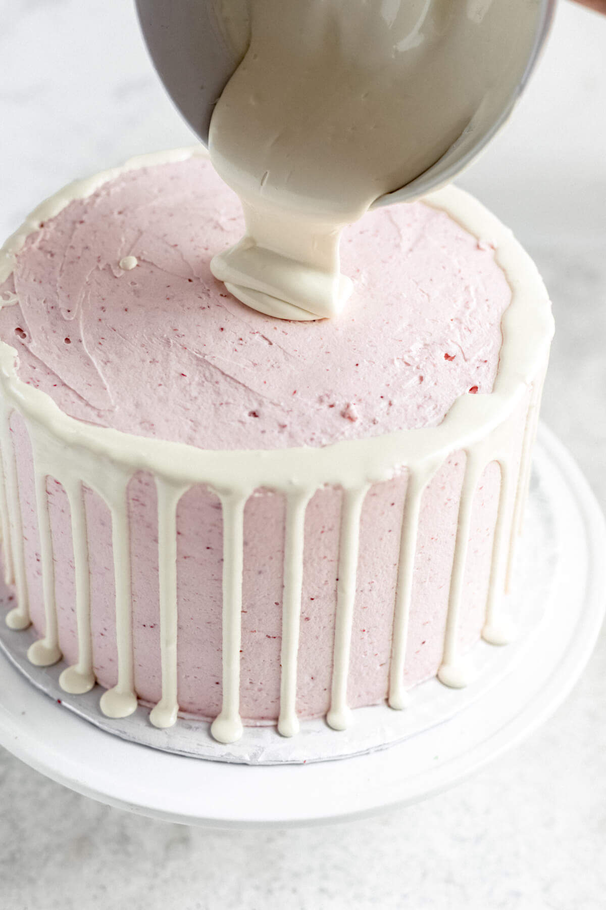 pouring white chocolate ganache into the centre of cake