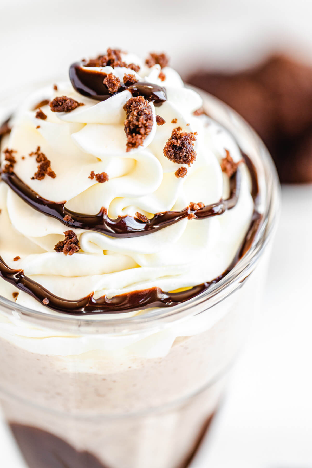 close up view of milkshake topped with whipped cream, a swirl of ganache and crumbled up brownies