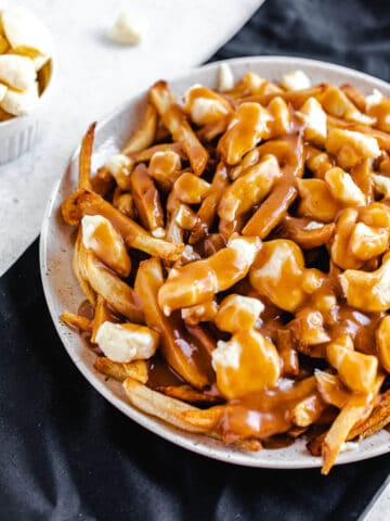 cheese, fries and gravy on a large plate that's on a black linen napkin