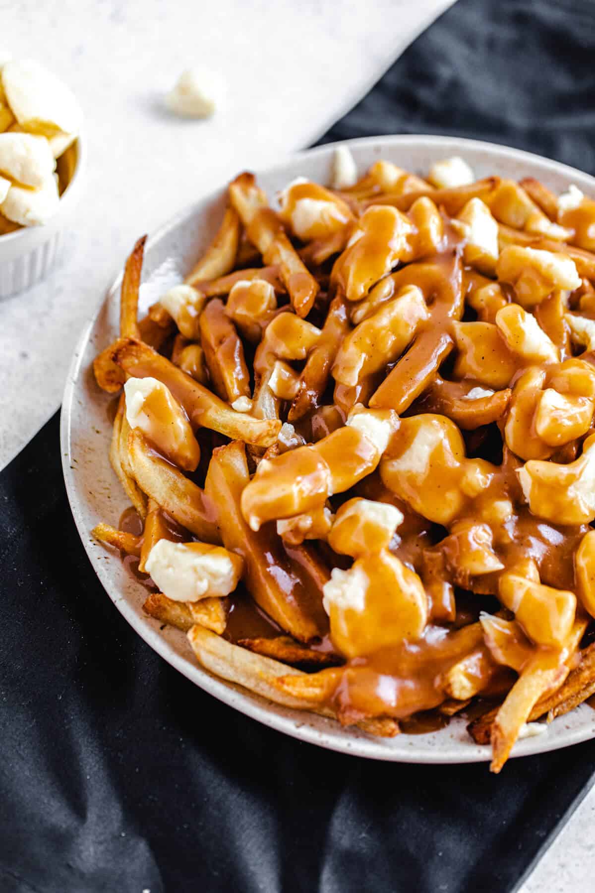 cheese, fries and gravy on a large plate that's on a black linen napkin