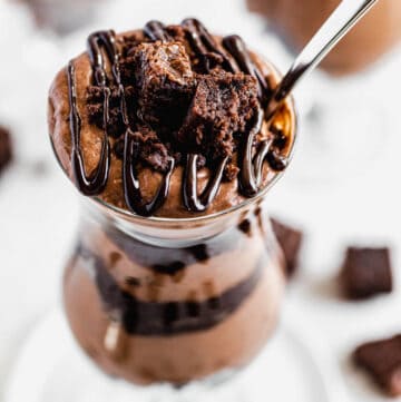 close up of chocolate mousse and brownies in a tall glass with a spoon