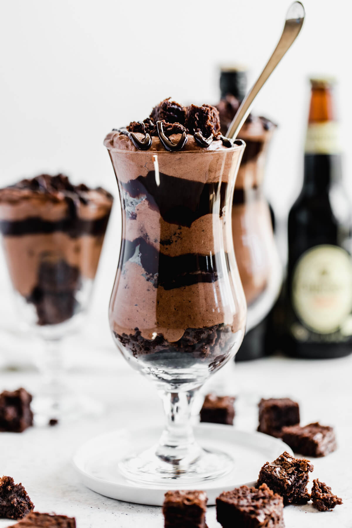 layers of mousse, ganache and brownie chunks in a glass with a spoon inside
