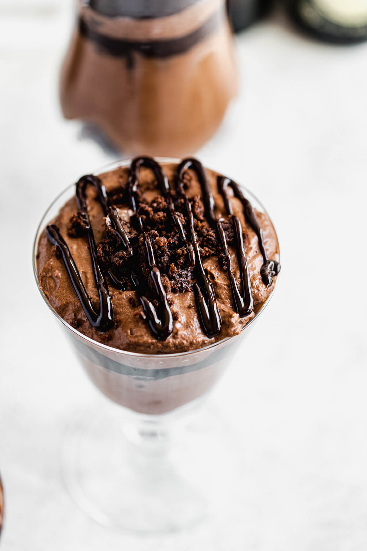 close up of mousse, brownie crumble and ganache drizzle in a small serving glass