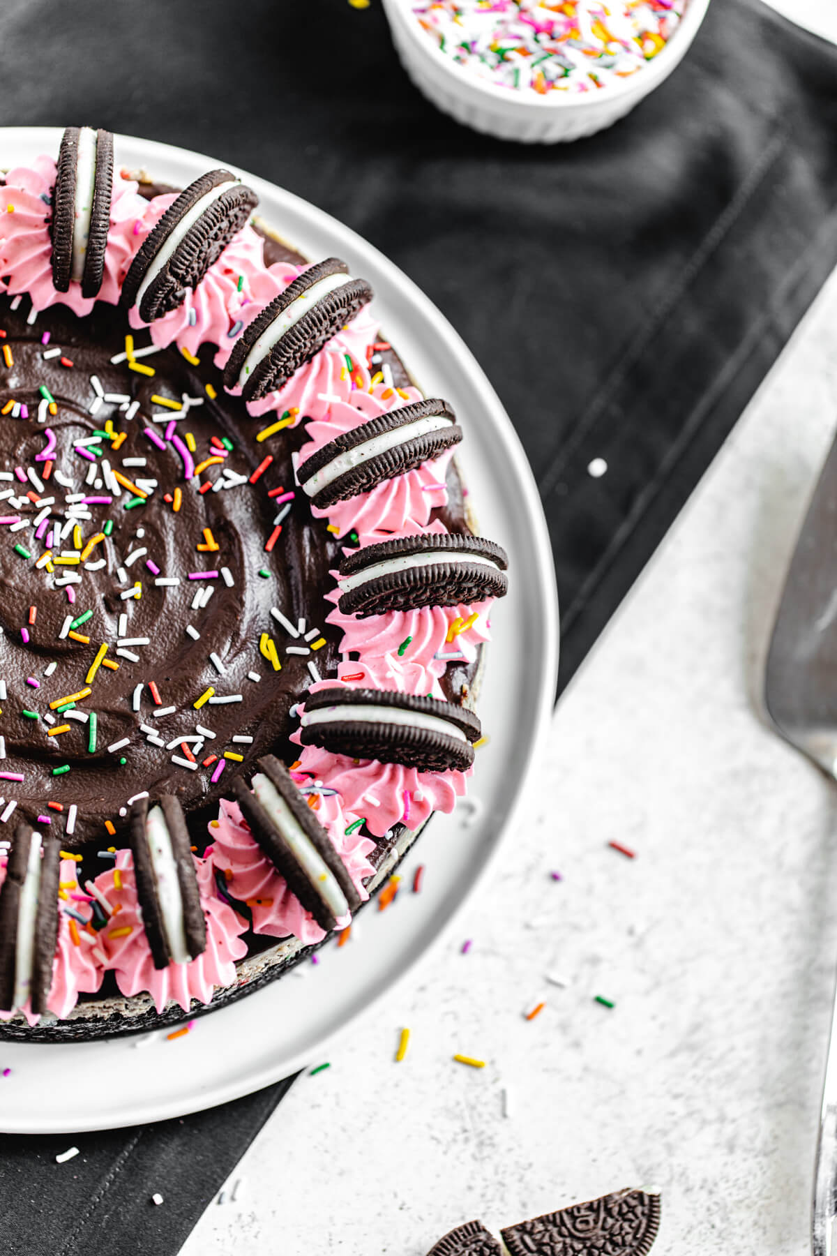 top view showing half of the cheesecake topped with pink whipped cream and Oreos