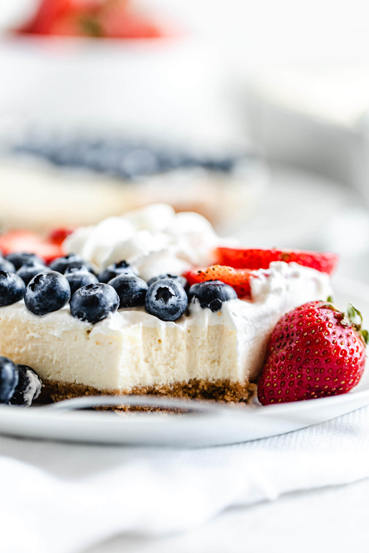 close up of cheesecake slice on a plate with bite taken out of it