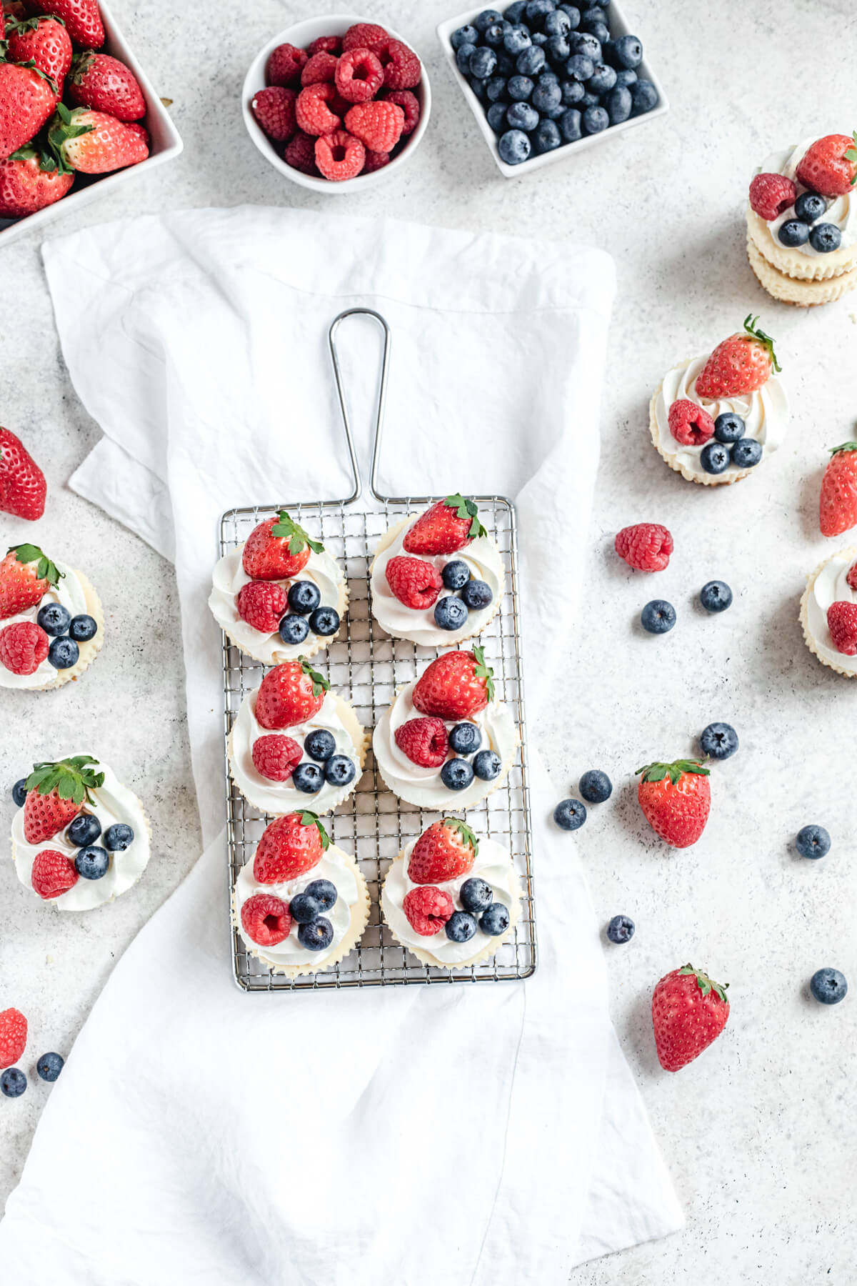 flat-lay view of cheesecakes topped with whipped cream, raspberries and strawberries